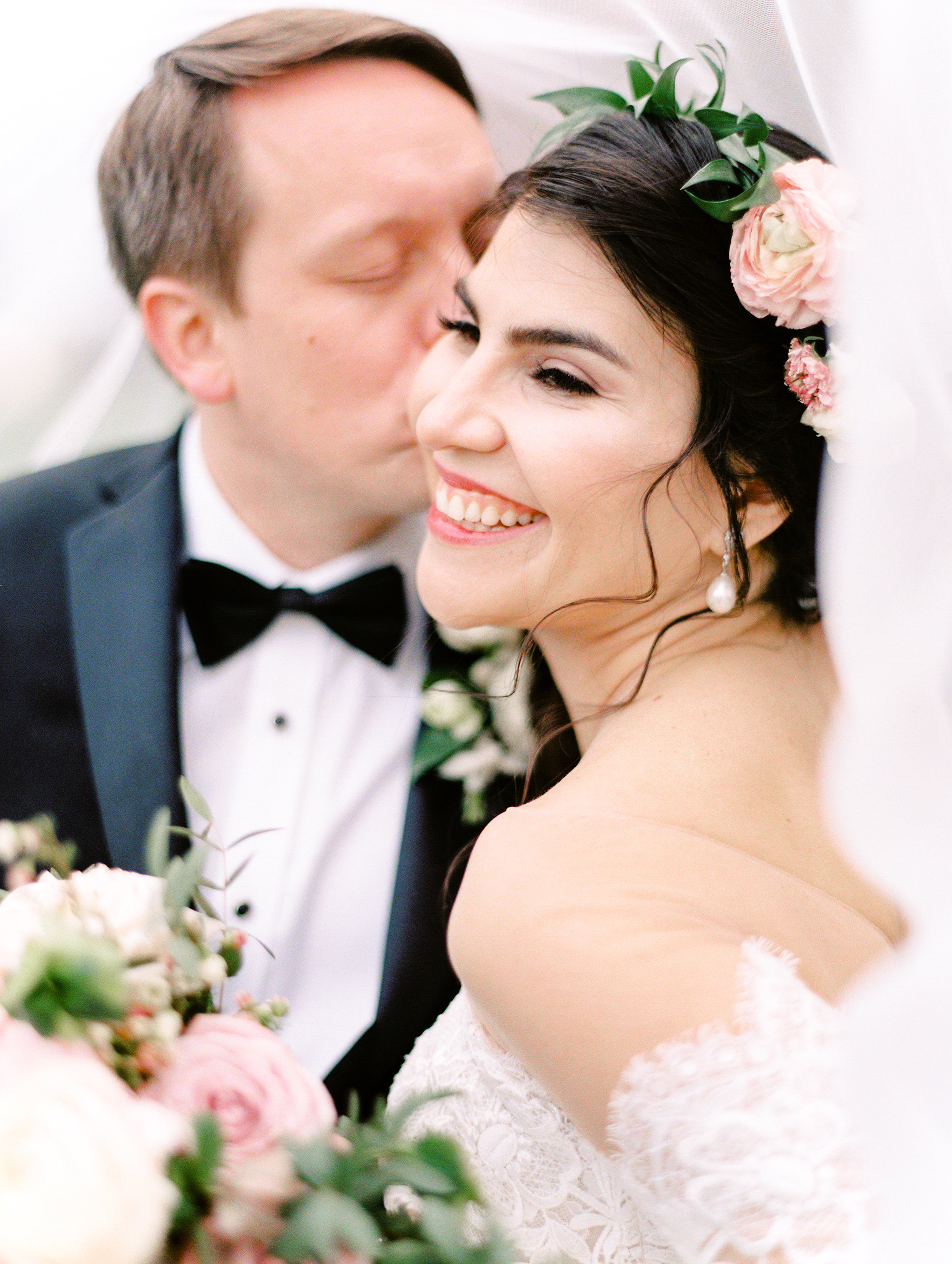 bride laughing with pink flowers in hair under veil