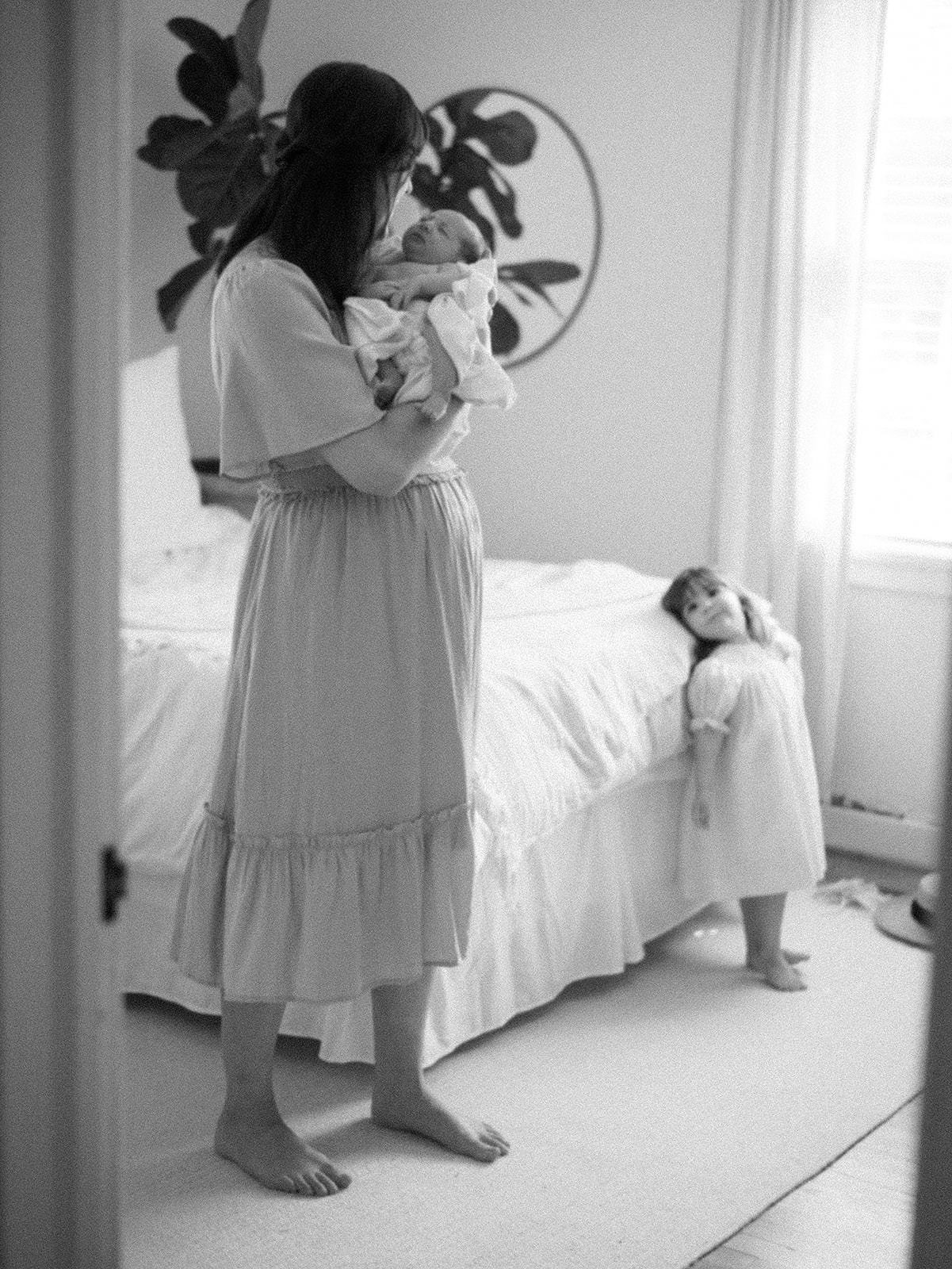 Mother cradles her newborn daughter with a loving smile, taken during an intimate family photoshoot